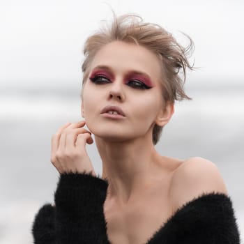 Face of amazing blonde woman with short hair and bright makeup looking away, posing outdoors on white natural background. Soft selective focus really makes Caucasian ethnicity fashion model stand out