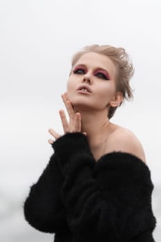 Portrait of sensual blonde woman taking playful pose. Caucasian fashion model raises her palms to neck, looking up thoughtfully. Soft selective focus really brings out her real expression and beauty