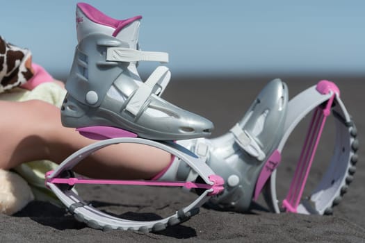 KAMCHATKA, RUSSIA - JUNE 15, 2022: Close-up view of pink Kangoo Jumps boots before outdoor fitness workout, aerobic exercising using trendy jumping boots on sandy beach on sunny summer day