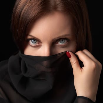 Portrait of shy woman covering her mouth and nose or face with scarf and looking at camera. Studio head shot of beautiful 40s brunette woman with gray eyes. Women's secrets concept.