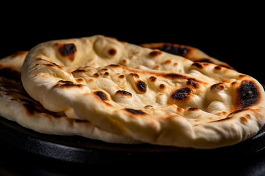 Freshly baked flatbread with charred spots on a dark background