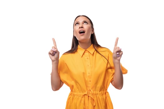 well-groomed slender young brunette lady is dressed in a bright yellow dress with short sleeves looks up with surprise.