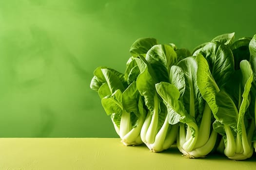 Fresh bok choy on a yellow surface against a green background.