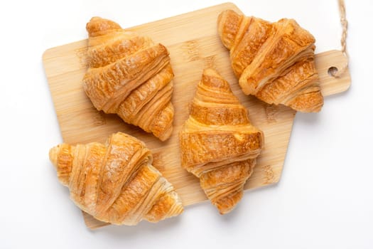 French croissants for breakfast. Freshly baked croissants on cutting board, isolated on white background, top view.