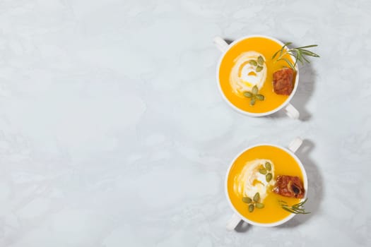 Pumpkin cream soup with smoked pork ribs and cream, top view, with copy space