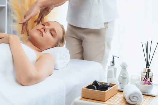 Caucasian woman enjoying relaxing anti-stress head massage and pampering facial beauty skin recreation leisure in dayspa modern light ambient at luxury resort or hotel spa salon. Quiescent