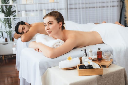 Blissful couple customer having exfoliation treatment in luxury spa salon with warmth candle light ambient. Salt scrub beauty treatment in health spa body scrub. Quiescent