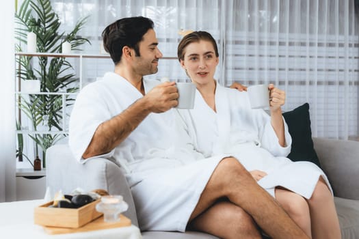 Beauty or body treatment spa salon vacation lifestyle concept with couple wearing bathrobe relaxing with drinks in luxurious hotel spa or resort room. Vacation and leisure relaxation. Quiescent