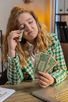 Caucasian young woman freelancer counting cash insufficient amount of money. Financial crisis. Bankruptcy. Poverty and destitution. Female girl businesswoman with laptop sitting at home office desk