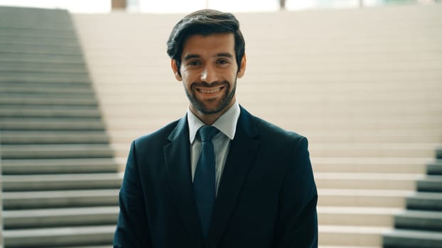 Portrait of smiling business man looking at camera while standing at stairs. Closeup of successful man smiling at camera while wearing business suit. Happy executive manager look at camera. Exultant.