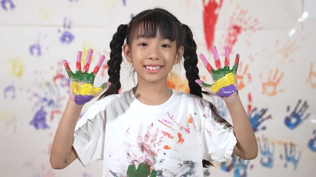 Asian happy student put hands up together show colorful stained hands. Smiling girl standing in front white background with stained hands while looking at camera. Creative activity concept. Erudition.