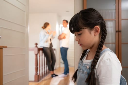 Stressed and unhappy young girl huddle in corner crying and sad while her parent arguing in background. Domestic violence at home and traumatic childhood develop to depression. Synchronos