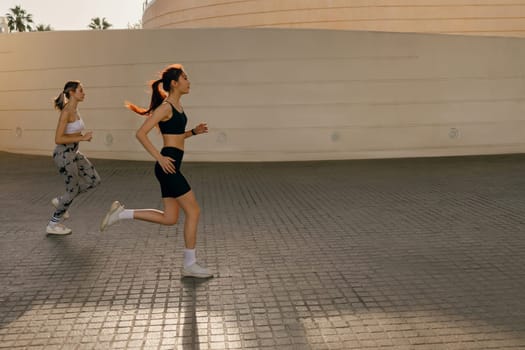 Active female friends in sportswear running outdoors on a sunny day . Reaching the goal