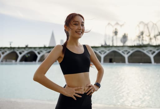 Pretty woman in sportswear have a rest after workout outside standing on building background