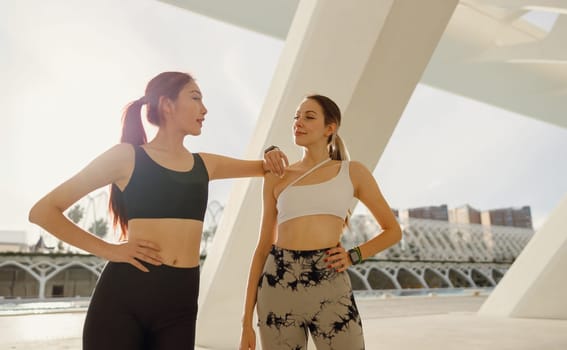 Two young female sportswomen have a rest after morning jogging outdoors. High quality photo