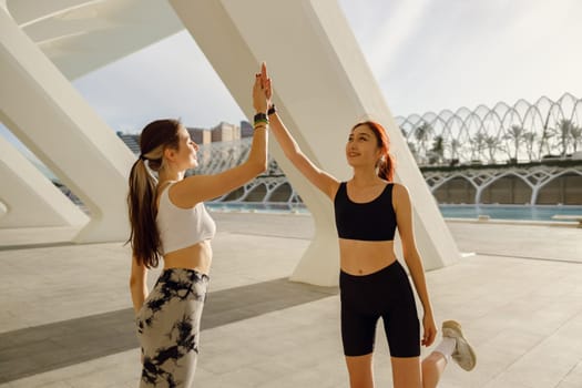 Happy female friends doing gesture of sport shake hand after exercising outside