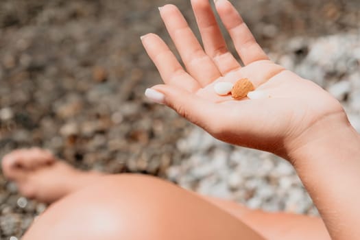 Woman eating milky almond nuts. A young caucasian woman choping fresh green almond after morning fitness yoga near sea. Only hands are visibly. Healthy vegan food. Slow motion. Close up