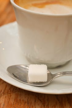 coffee cup and sugar cube on table.