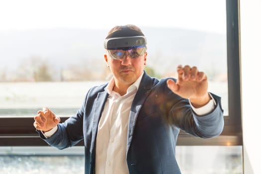 Frontal view of a businessman wearing mixed reality goggles touching interactive screen in the office