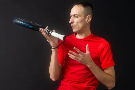 Professional monitor of paddel holding a black racket. Man paddel player playing a match in the open. High quality photo