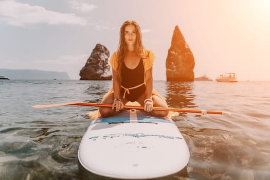 Close up shot of beautiful young caucasian woman with black hair and freckles looking at camera and smiling. Cute woman portrait in a pink bikini posing on a volcanic rock high above the sea