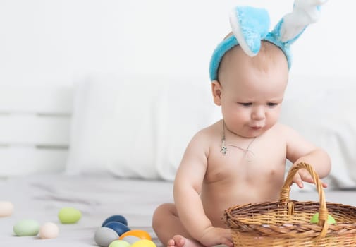 Mother and child with colorful eggs. Mom and baby with bunny ears. Parent and kid play indoors in spring. Family celebrating Easter.
