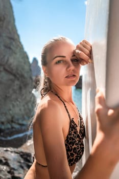 Woman in black bikini sap sea. Portrait of a happy girl on the background of a surfboard in the sea on a sunny summer day.