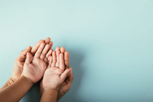 Close-up top view of family hands stack on isolated background. Parents and kid hold empty space together symbolizing support and love for Family and Parents Day.
