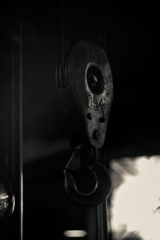 Metal hook from a crane against the background of a workshop. A piece of metal or other material, curved or bent back at an angle, for catching hold of or hanging things on.