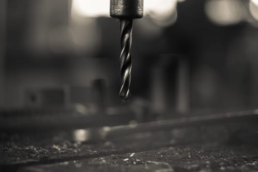 A part of a workbench with a metal drill and shavings on it