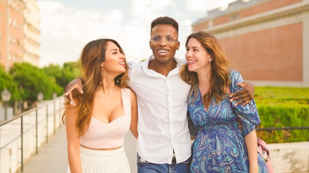 Three people smiling while walking together in the street