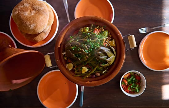 Directly above a delicious yummy healthy vegetarian meal with steamed artichokes in tagine clay pot. Moroccan crockery, culture, cuisine and traditions. Extreme close-up photo for food blog