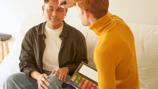 Gay man applying eye shadow to a man at home