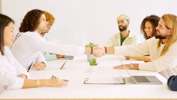 Hispanic men shaking hands closing a deal in a meeting room