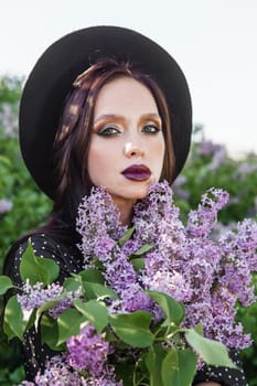 A fashionable girl with dark hair, a spring portrait in lilac tones in summer. Bright professional makeup