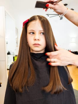 Gentle hands maneuver a hair dryer through a young girl's newly cut hair, showcasing the drying process after a meticulous trim. The warmth of the dryer breathes life into her locks, as they transform from damp to styled with care and expertise.