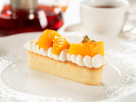 Persimmon tart with whipped cream. Delicious soft and creamy tart with fresh sweet persimmons on white plate on restaurant table background. Dessert idea with persimmons fruit