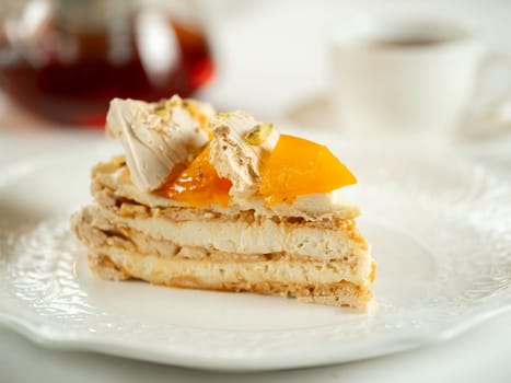 Puff layered cake with cream of cream-cheese, decorated fresh persimmons. Delicious and eye-catching piece of layered cake decorated crispy meringue and orange persimmons