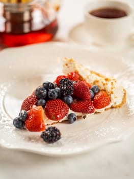 Piece of appetizing cheesecake or berry tart with whipped cream on restaurant table. Delicious new york cheesecake with berries mix. Vertical, copy space