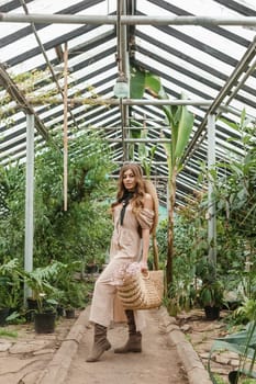 A beautiful young woman takes care of plants in a greenhouse. The concept of gardening and an eco-friendly lifestyle