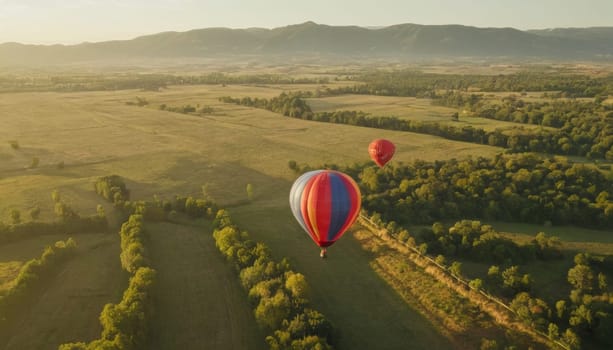 A breathtaking view of colorful hot air balloons soaring over a picturesque historic village nestled among lush greenery and mountains at sunrise.