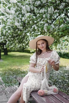 An attractive long-haired woman walks in the spring in the park of blooming apple trees. Spring portrait of a woman