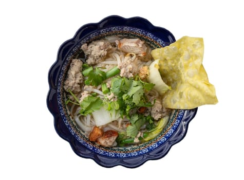 Rice stick noodles soup topped with Minced pork, Crispy pork, Fried wontons, Chinese cabbage, Yard long beans, Bean sprout and Coriander in Ceramic bowl isolated on white background with clipping path. Top view, Selective focus.