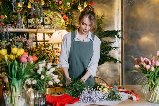 A woman in her florist shop collects bouquets of flowers. The concept of a small business. Bouquets of tulips for the holiday on March 8