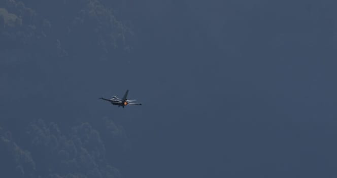 Mollis Switzerland August 19 2023: Lone jet plane flies above a lush green forest canopy, set against a clear blue sky
