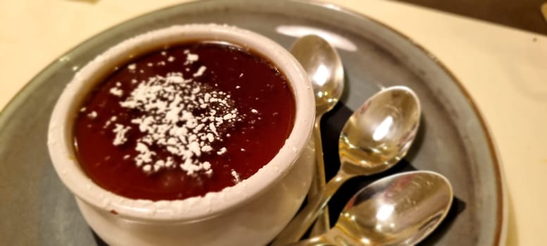 Rich chocolate pudding sprinkled with sugar, served in a ceramic bowl