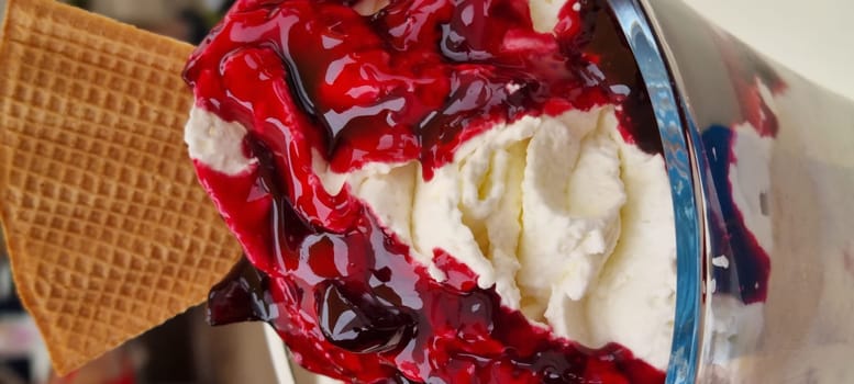 Delicious ice cream sundae drizzled with cherry sauce and a crispy wafer; perfect for a sweet treat