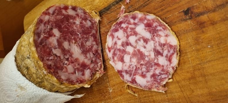 Close-up of handcrafted cured salami slices, showcasing meat textures and marbling. Vertical image