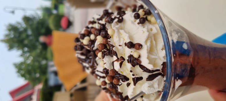 Close-up view of a chocolate sundae topped with whipped cream and chocolate balls