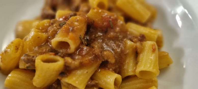 Close-up shot of delicious rigatoni pasta topped with rich and meaty bolognese sauce